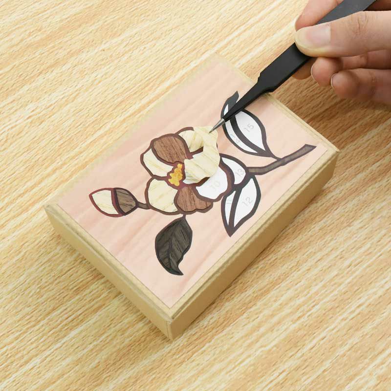 下絵をフタに貼り、はさみで切ってシール状になった天然木のパーツを下絵に貼ります